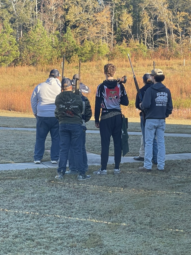 Shooters gathered at the trap line with shotguns shouldered on a frosty morning