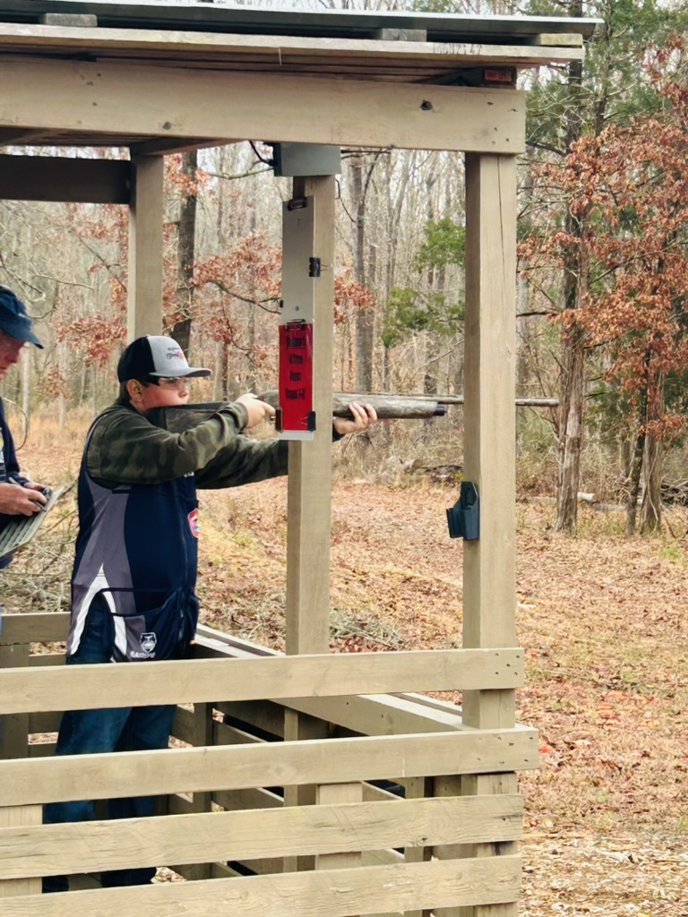 Shooter mounted on a shotgun at a covered trap station in the woods