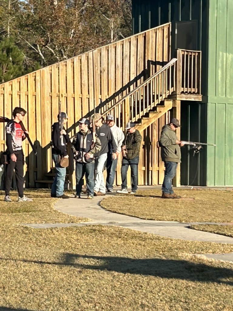 Shooters and coaches gathered beside the skeet house on a sunny winter morning