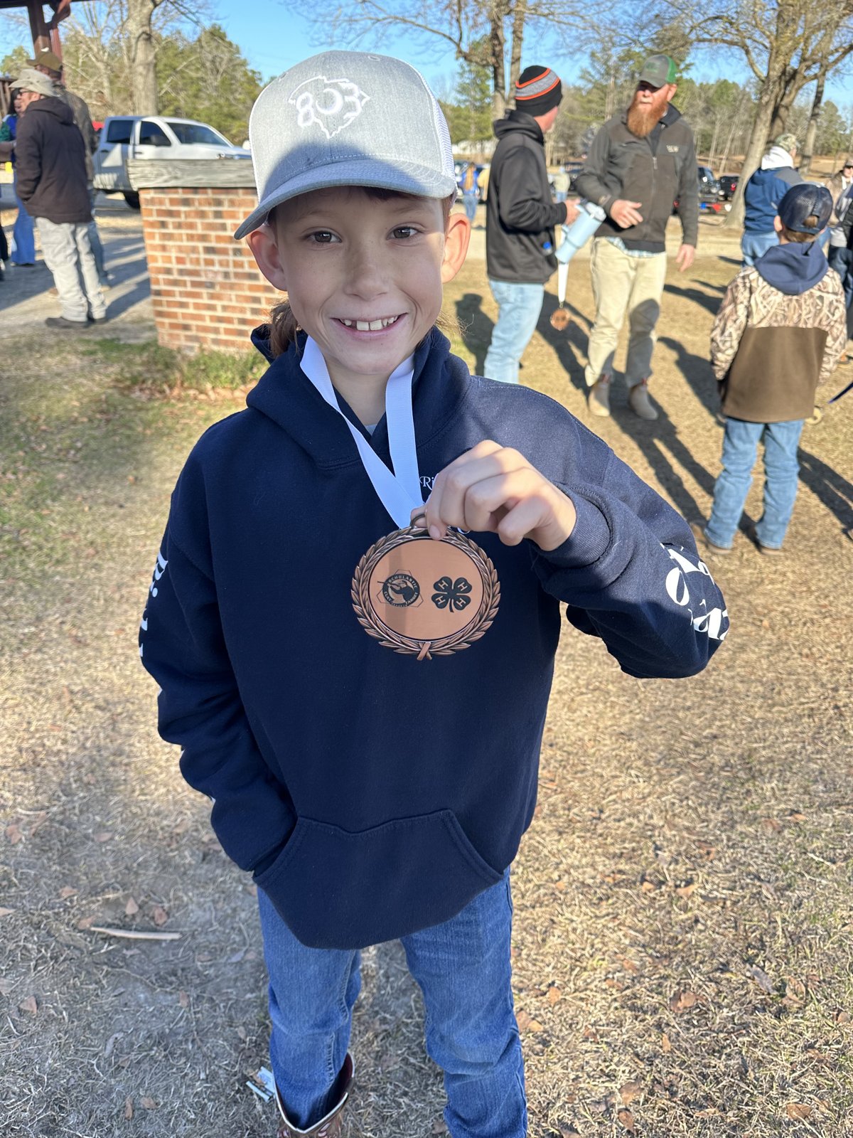 A young Richland Creek Top Guns shooter smiling and holding up his medal after a match