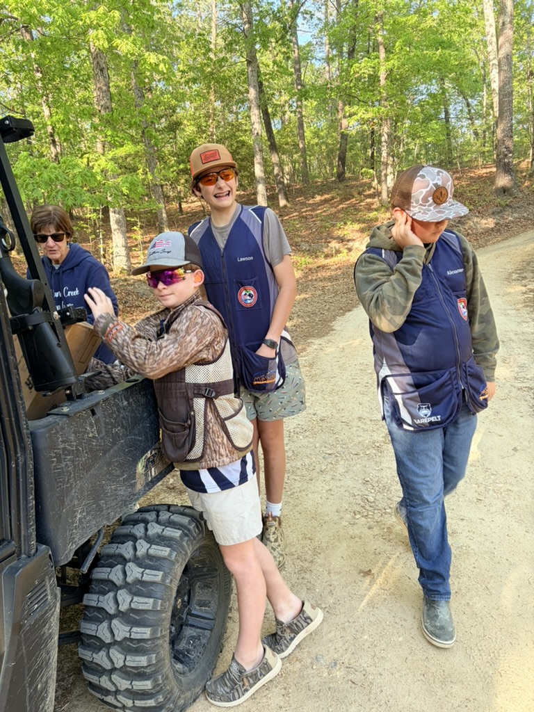 Shooters in team vests on a dirt road between sporting clays stations